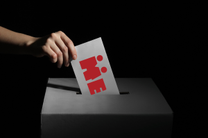 Person som plasserer stemmeseddel med foreningens logo på, i mørket.
